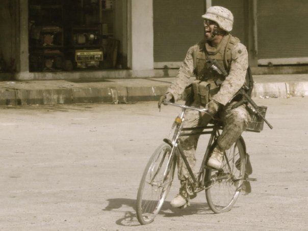 Picture of Patrick on a bicycle in full gear while deployed to Iraq.  His favorite war picture ever.